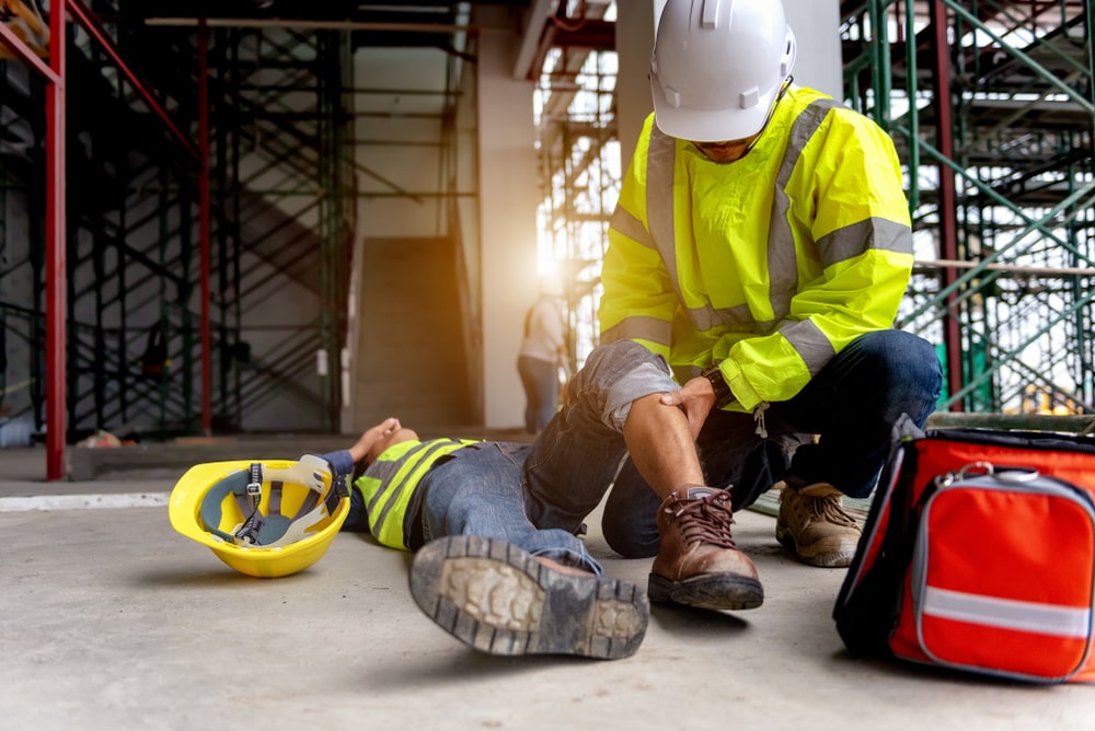 Construction worker falls from scaffolding; safety team assists. A personal injury lawyer in New Orleans could help.