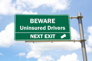 Green sign warning of Uninsured Drivers, symbolizing UM coverage importance for a personal injury lawyer in New Orleans.